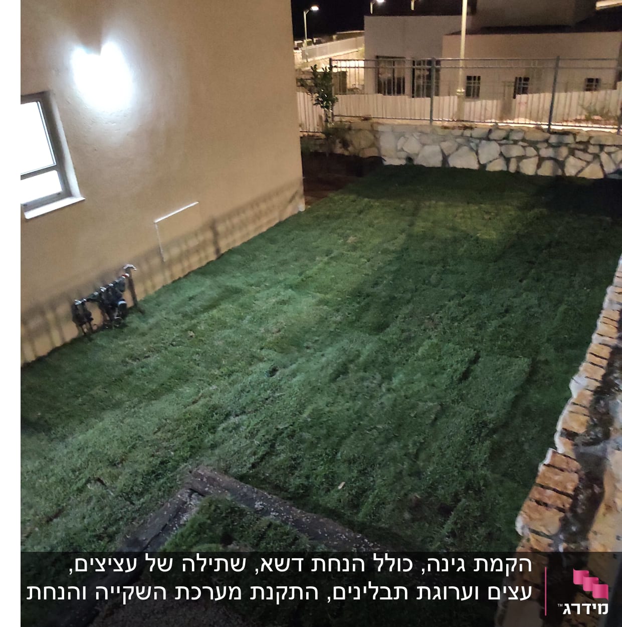 דשא חדש מונח בחצר ליד קיר אבן